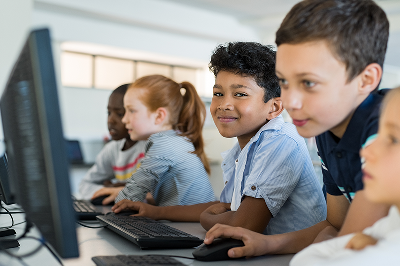 Group of five elementary school students on desktop computers